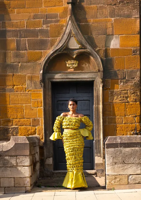 Portrait of a woman in a mustard gown by a church door, photographed by Imisi Bamiro, Coventry photographer